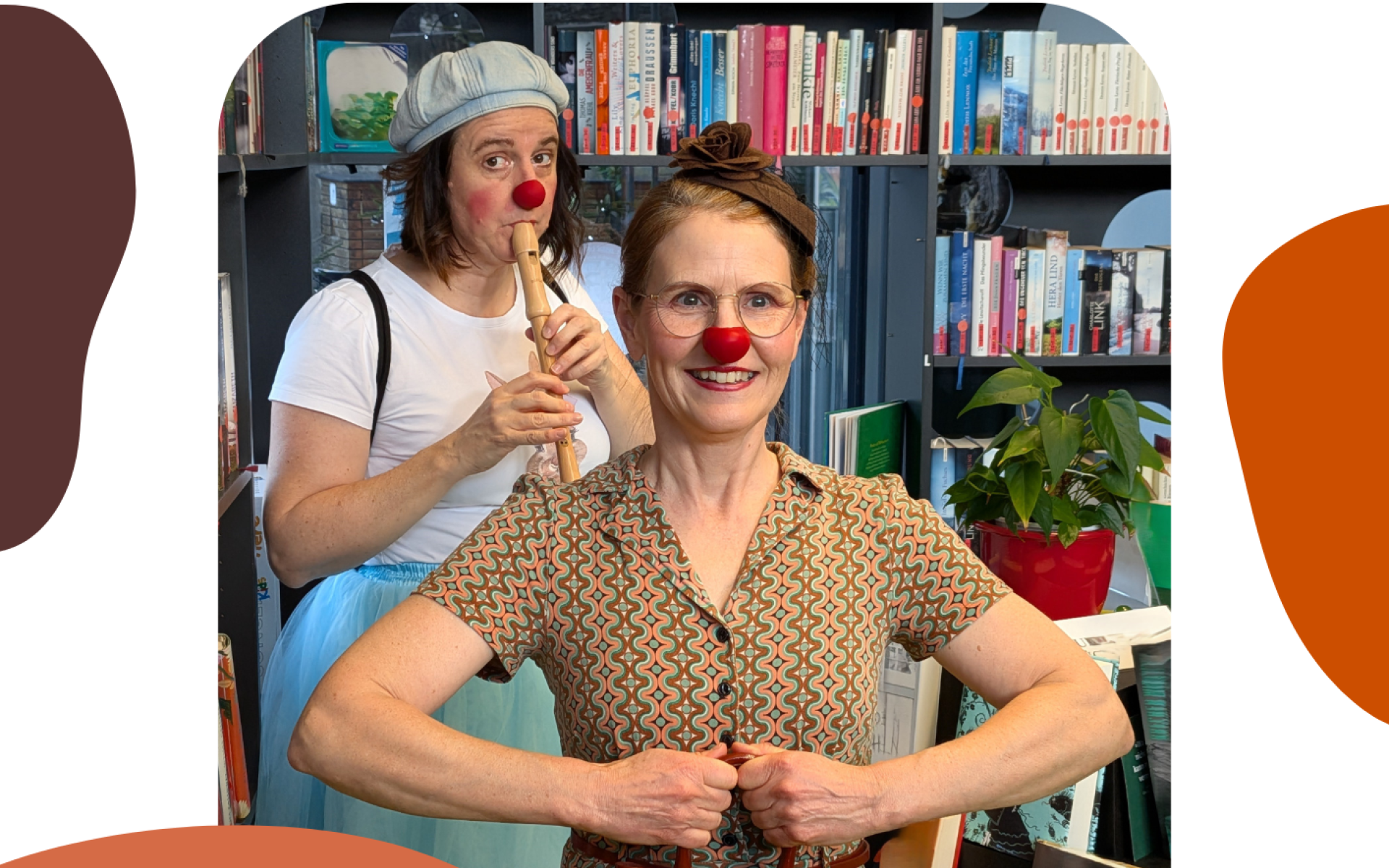 Die Bücherei Clowndamen Jessi und Konstanze stehen mit ihren roten Clownnasenvor einem Bücherregal